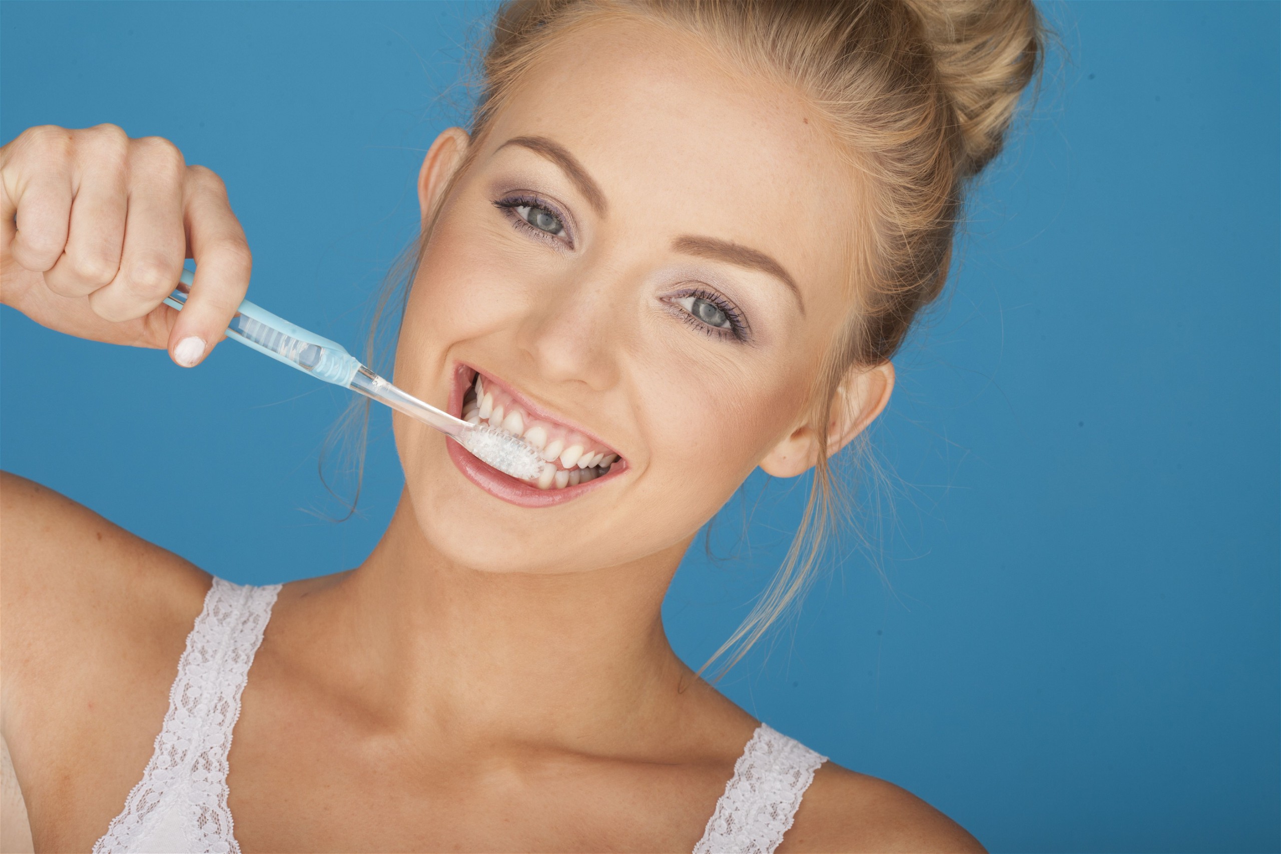Young Blonde Woman Happily Brushing Her teeth