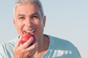 Mature Man With Sky Blue Shirt Eating Red Apple Outdoors