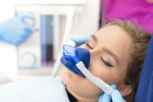 Patient Under Sedation With Breathing Mask Sleeping on Dental Chair